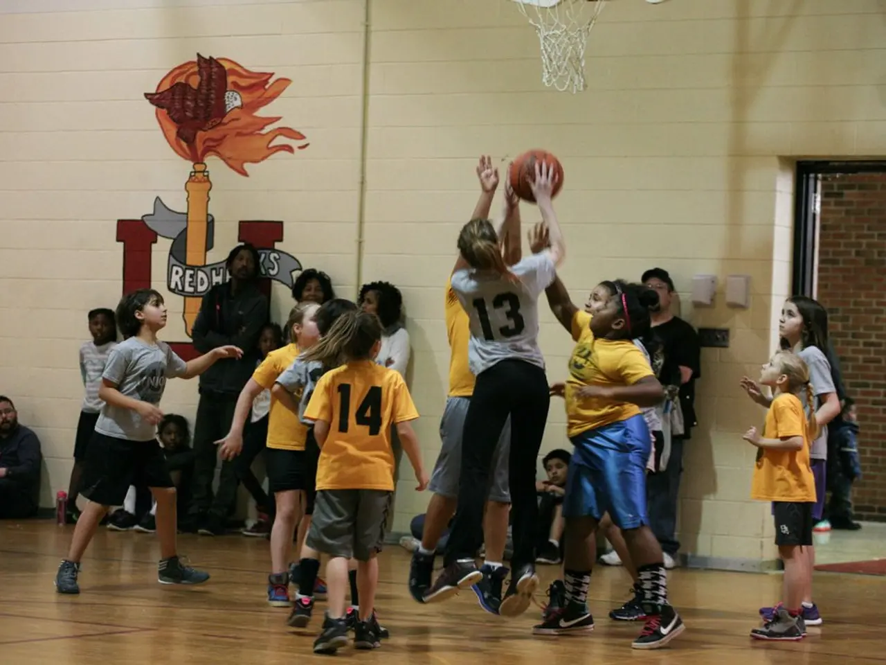 In this picture, we see children in yellow color and grey color t-shirt are playing basketball. The...